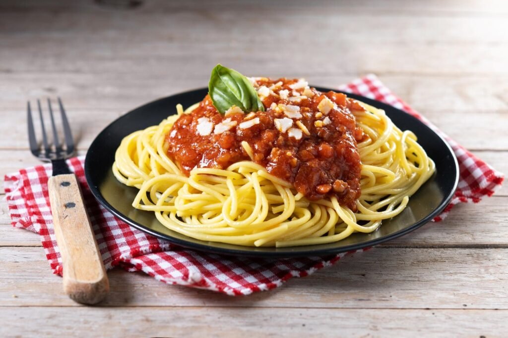 a plate of spaghetti with sauce and basil on a napkin