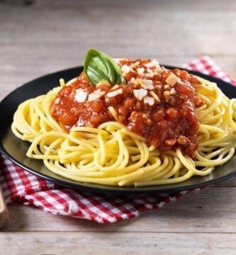 a plate of spaghetti with sauce and basil on a napkin