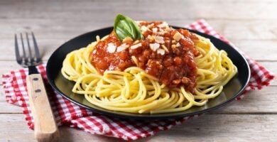 a plate of spaghetti with sauce and basil on a napkin